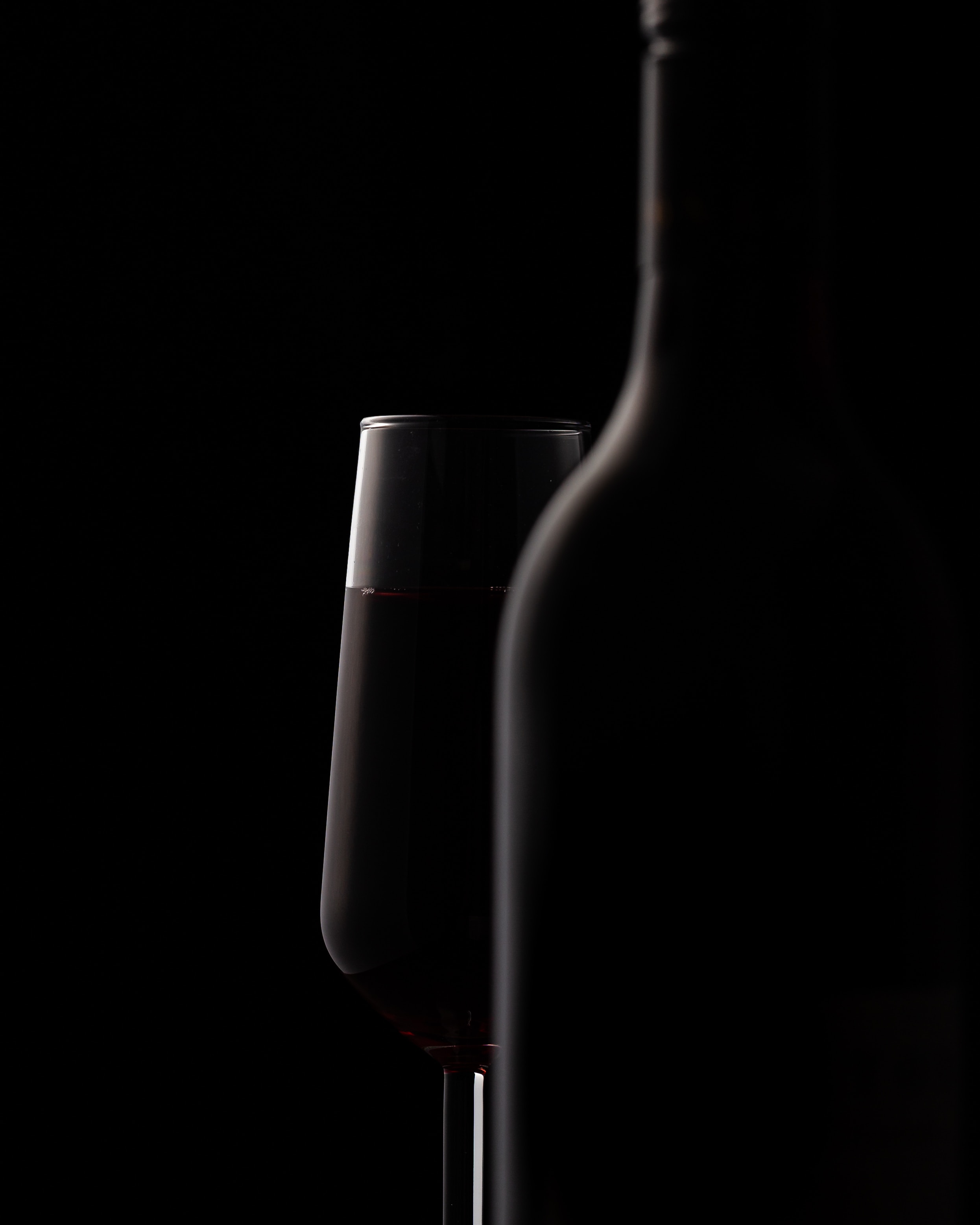 Close up d'une bouteille de vin et d'un verre de vin, noir sur noir